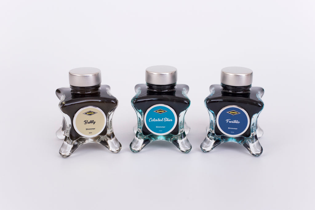 Group of three glass bottles of 50ml Diamine Teal Edition Inkvent shimmer fountain pen ink, Bubbly, Celestial Skies & Frostbite. Sitting in front of a white background.