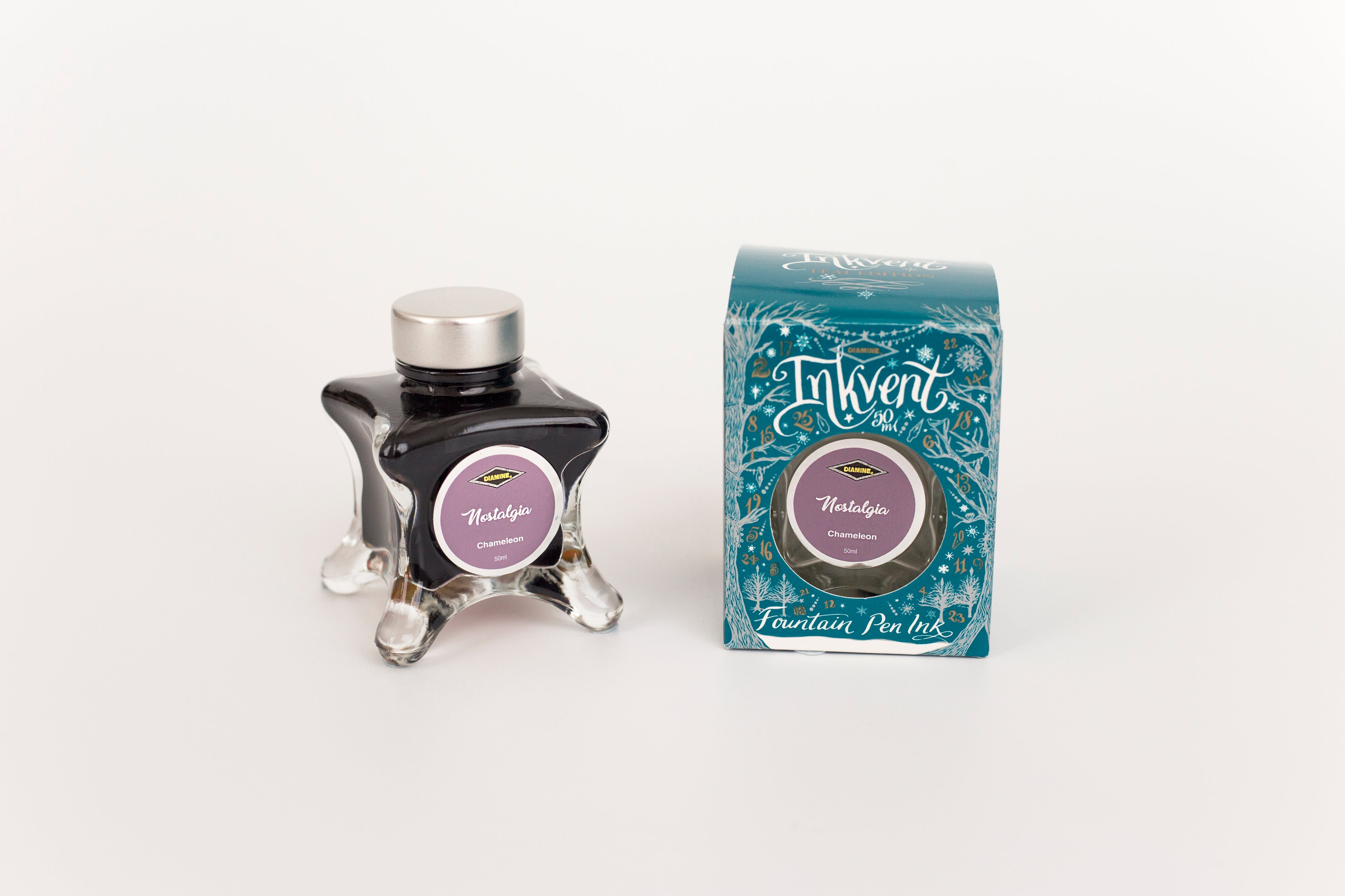 Glass bottle of 50ml Diamine Teal Edition Inkvent Nostalgia fountain pen ink next to Teal coloured and Christmas-themed packaging box, in front of a white background.