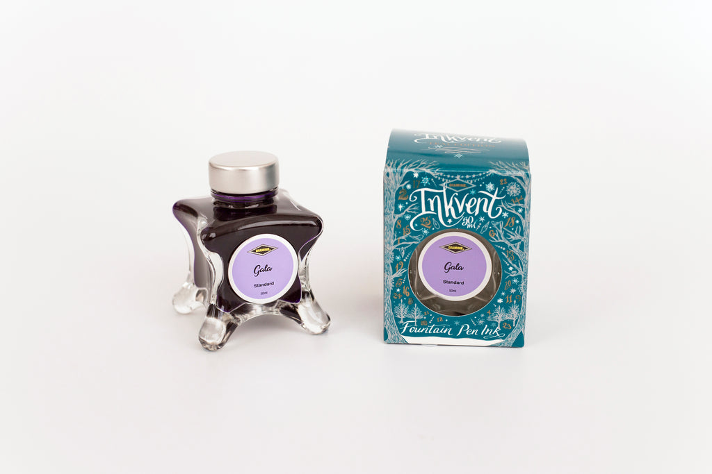Glass bottle of 50ml Diamine Teal Edition Inkvent Gala fountain pen ink next to Teal coloured and Christmas-themed packaging box, in front of a white background.