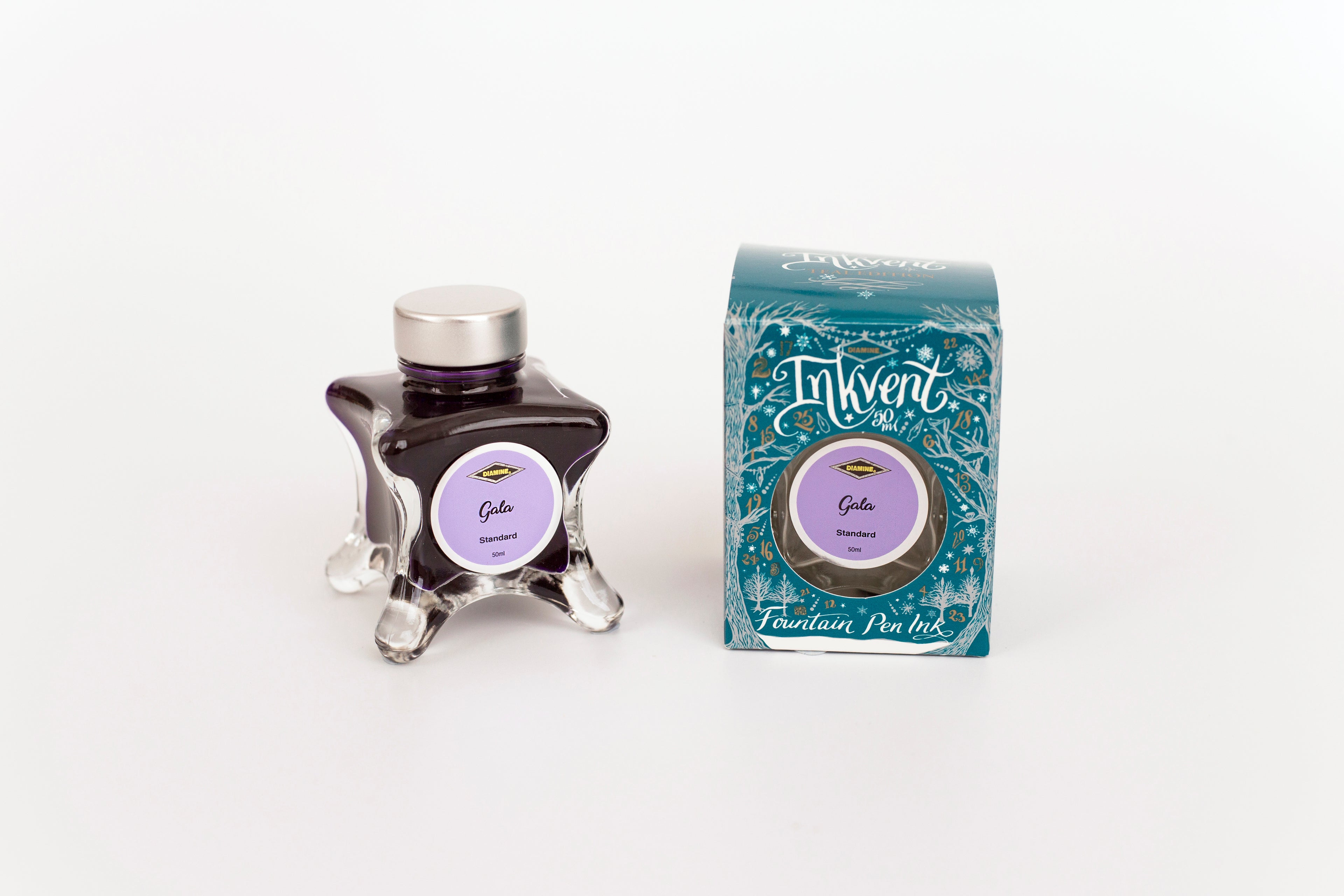 Glass bottle of 50ml Diamine Teal Edition Inkvent Gala fountain pen ink next to Teal coloured and Christmas-themed packaging box, in front of a white background.