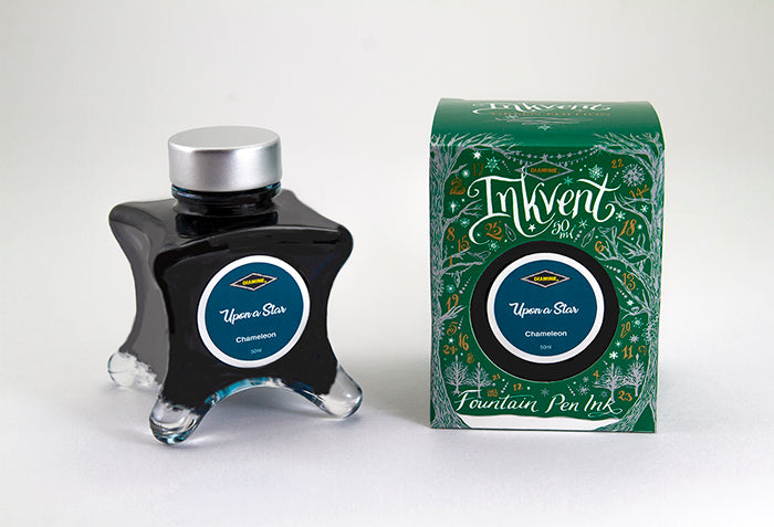 A glass bottle of 50ml Diamine Green Edition Inkvent Upon a Star chameleon fountain pen ink next to packaging box, in front of a white background.