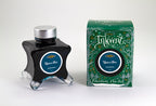 A glass bottle of 50ml Diamine Green Edition Inkvent Upon a Star chameleon fountain pen ink next to packaging box, in front of a white background.