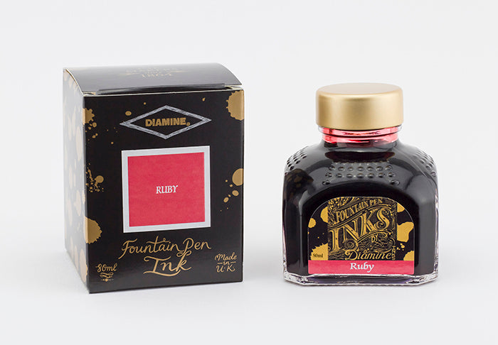 A glass bottle of 80ml Diamine Ruby fountain pen ink next to its packaging box, in front of a white background.