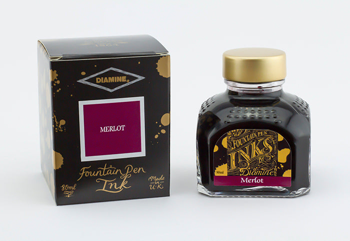 A glass bottle of 80ml Diamine Merlot fountain pen ink next to its packaging box, in front of a white background.