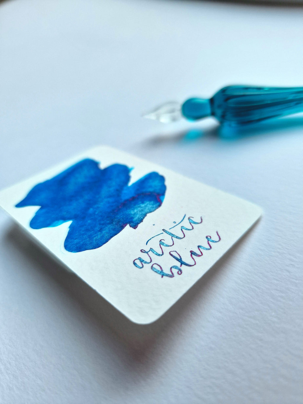 A colour swatch and writing swatch of Diamine Arctic Blue shimmering fountain pen ink.