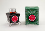 A glass bottle of 50ml Diamine Green Edition Inkvent Cardinal fountain pen ink next to packaging box, in front of a white background.