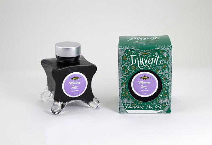 A glass bottle of 50ml Diamine Green Edition Inkvent Memory Lane fountain pen ink next to packaging box, in front of a white background.