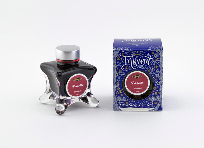 A glass bottle of 50ml Diamine Blue Edition Inkvent Poinsettia fountain pen ink next to packaging box, in front of a white background.