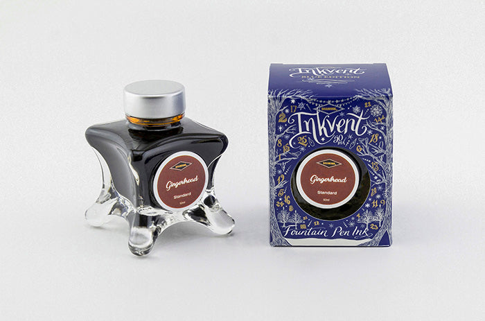 A glass bottle of 50ml Diamine Blue Edition Inkvent Gingerbread fountain pen ink next to packaging box, in front of a white background.