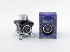 A glass bottle of 50ml Diamine Blue Edition Inkvent Midnight Hour sheening fountain pen ink next to packaging box, in front of a white background.