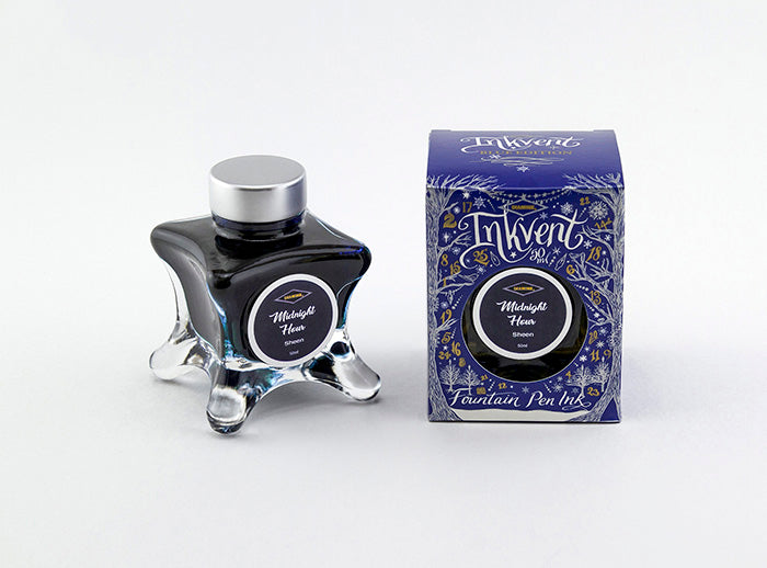 A glass bottle of 50ml Diamine Blue Edition Inkvent Midnight Hour sheening fountain pen ink next to packaging box, in front of a white background.