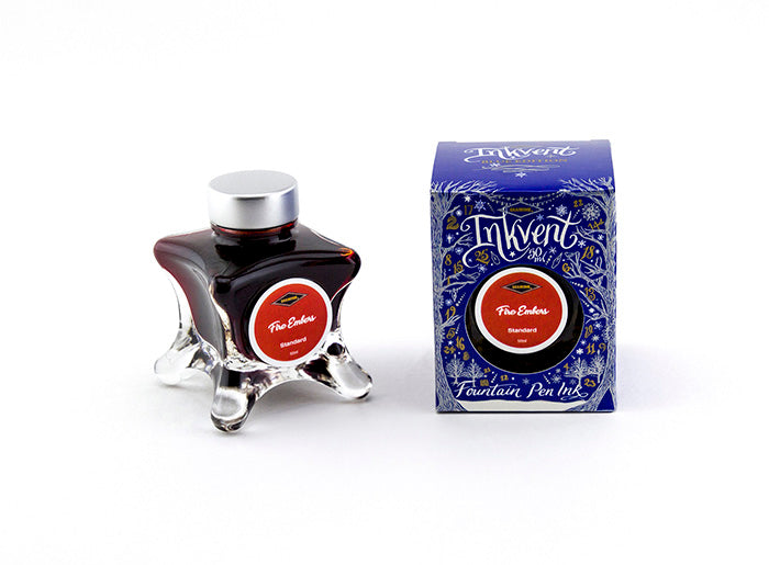 A glass bottle of 50ml Diamine Blue Edition Inkvent Fire Embers fountain pen ink next to packaging box, in front of a white background.