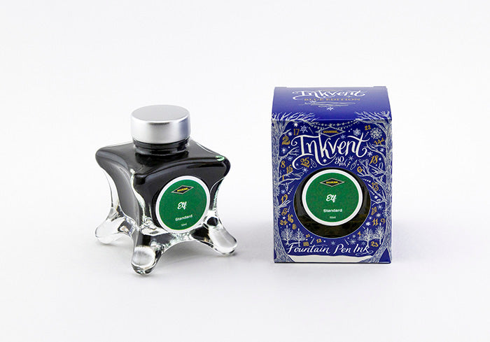 A glass bottle of 50ml Diamine Blue Edition Inkvent Elf fountain pen ink next to packaging box, in front of a white background.