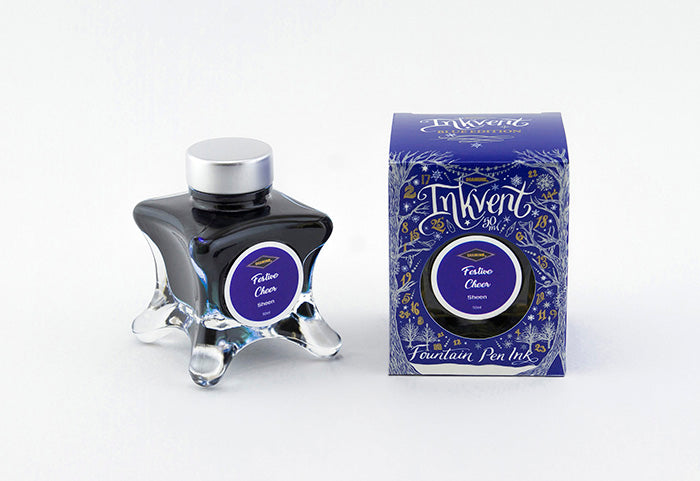 A glass bottle of 50ml Diamine Blue Edition Inkvent Festive Cheer sheening fountain pen ink next to packaging box, in front of a white background.