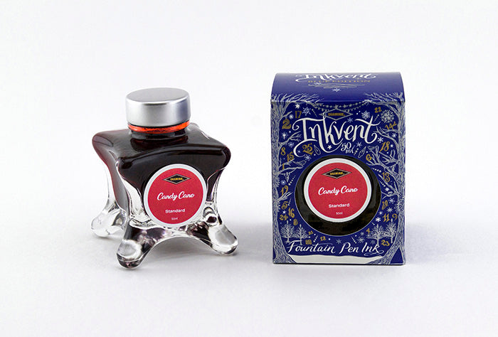 A glass bottle of 50ml Diamine Blue Edition Inkvent Candy Cane fountain pen ink next to packaging box, in front of a white background.