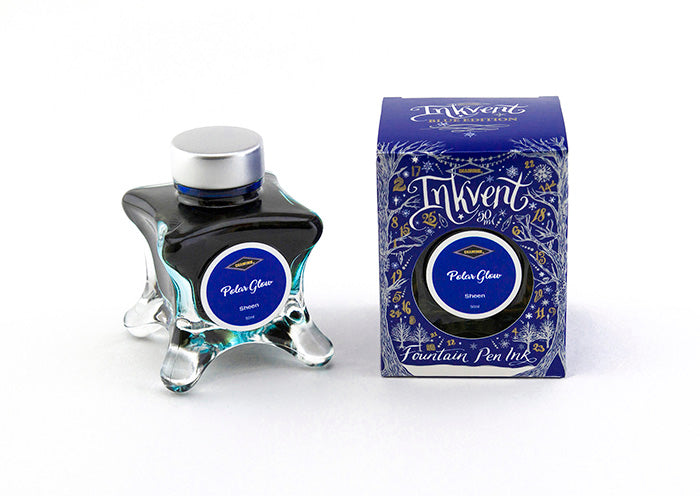 A glass bottle of 50ml Diamine Blue Edition Inkvent Polar Glow Sheening fountain pen ink next to packaging box, in front of a white background.