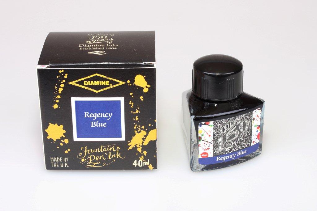 A glass bottle of 40ml Diamine 150th Anniversary Regency Blue fountain pen ink next to packaging box, in front of a white background.