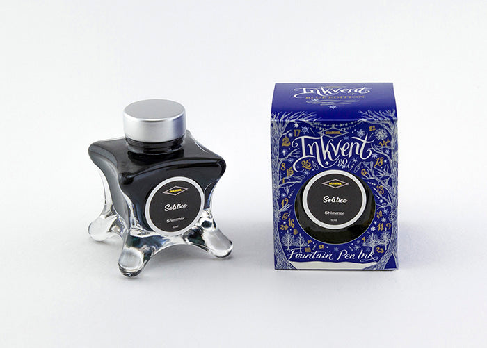 A glass bottle of 50ml Diamine Blue Edition Inkvent Solstice shimmer fountain pen ink next to packaging box, in front of a white background.